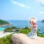 A small girl on a rock, overlooking the ocean, symbolizes the joy of discovery in a travel experience.