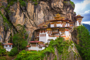 A breathtaking view of the Tiger's Nest Monastery in Bhutan, perched high on a cliff, surrounded by lush greenery.