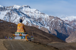 A serene Buddhist statue overlooks a majestic mountain range, embodying tranquility in a travel destination.
